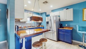A kitchen with blue walls, white cabinets, a stainless steel refrigerator, a wooden island with stools, and a hanging light fixture. - 4 Mi to Dtwn: Pet-Friendly Getaway in Phoenix (Phoenix)