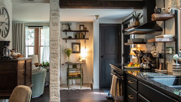 A modern kitchen with dark cabinetry, a central island, and a dining area with a chair and table. - Charming 2BR Cottage · Near Lake Lookout · Wine Tasting Included · Pet Friendly (Portland)