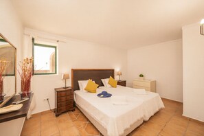 A bedroom with a bed, nightstands, a dresser, a mirror, and a window.