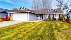 A two-story house with a garage, a well-maintained lawn, and a flag. - Tranquil Redmond Retreat: Relax & Explore Outdoors (Redmond)