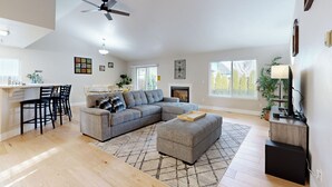 A spacious living room with a sectional sofa, ottoman, and a dining area with chairs. - Tranquil Redmond Retreat: Relax & Explore Outdoors (Redmond)
