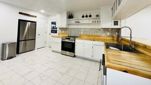 A modern kitchen with white cabinets, stainless steel appliances, and a wooden countertop.