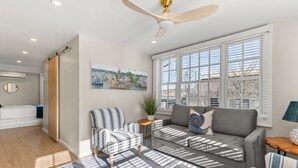 A modern living room with a grey sofa, striped armchair, and a small side table with a plant.