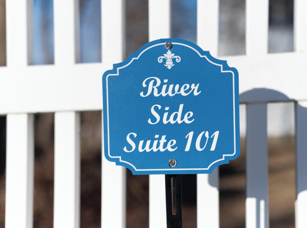 Skilt med teksten 'River Side Suite 101' monteret på en stolpe.