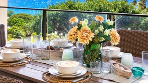 Un tavolo apparecchiato con piatti, ciotole, bicchieri e un vaso di fiori, con vista su un panorama suggestivo.