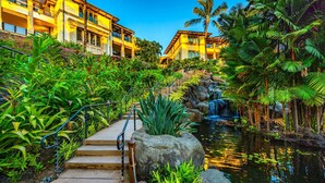 Un resort con una cascata, vegetazione lussureggiante e un edificio a più piani con balconi.