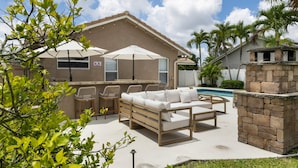 An outdoor patio with a pool, lounge chairs, and a barbecue area. - Spacious Family Home | Saltwater Pool | Game Room (Palm Beach County)