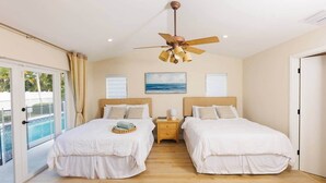 A hotel room with two beds, a ceiling fan, a nightstand, and a view of a swimming pool. - Spacious Family Home | Saltwater Pool | Game Room (Palm Beach County)