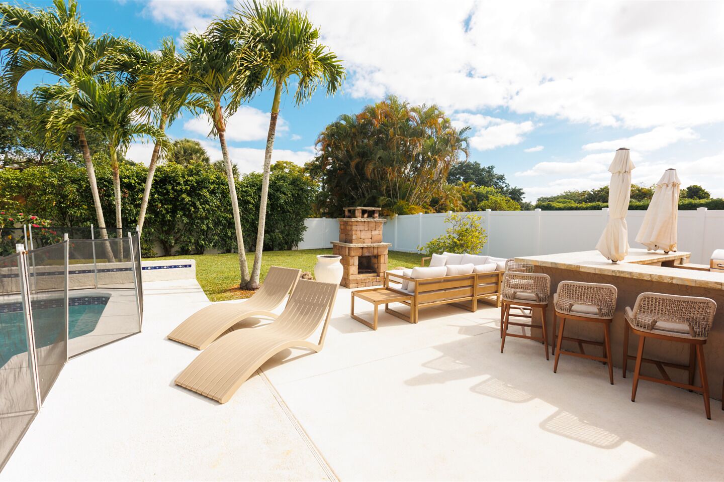 A poolside area with lounge chairs, a bar, and a fire pit.