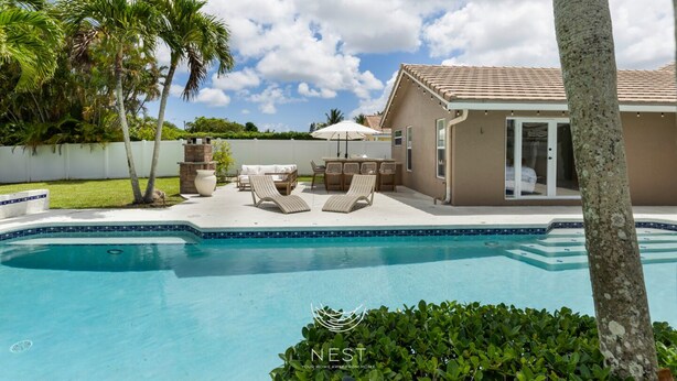 A pool area with lounge chairs, a barbecue, and a covered patio. - Spacious Family Home | Saltwater Pool | Game Room (Palm Beach County)