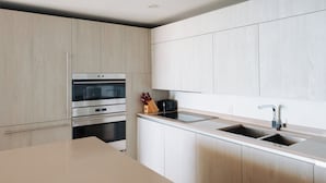 A modern kitchen with light wood cabinetry, stainless steel appliances, and a double sink. - Oceanfront 36th Floor Condo with Stunning Views Resort and Beach Access (Hollywood)