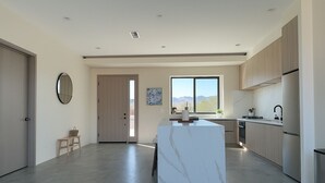 A modern kitchen with a marble island, stainless steel appliances, and a view of mountains through the window. - 4 Bedrooms, 3 Bathrooms, luxury homes for a vacation getaway. (Joshua Tree)
