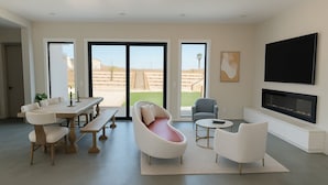A modern living room with a dining area, a fireplace, and large windows. - 4 Bedrooms, 3 Bathrooms, luxury homes for a vacation getaway. (Joshua Tree)