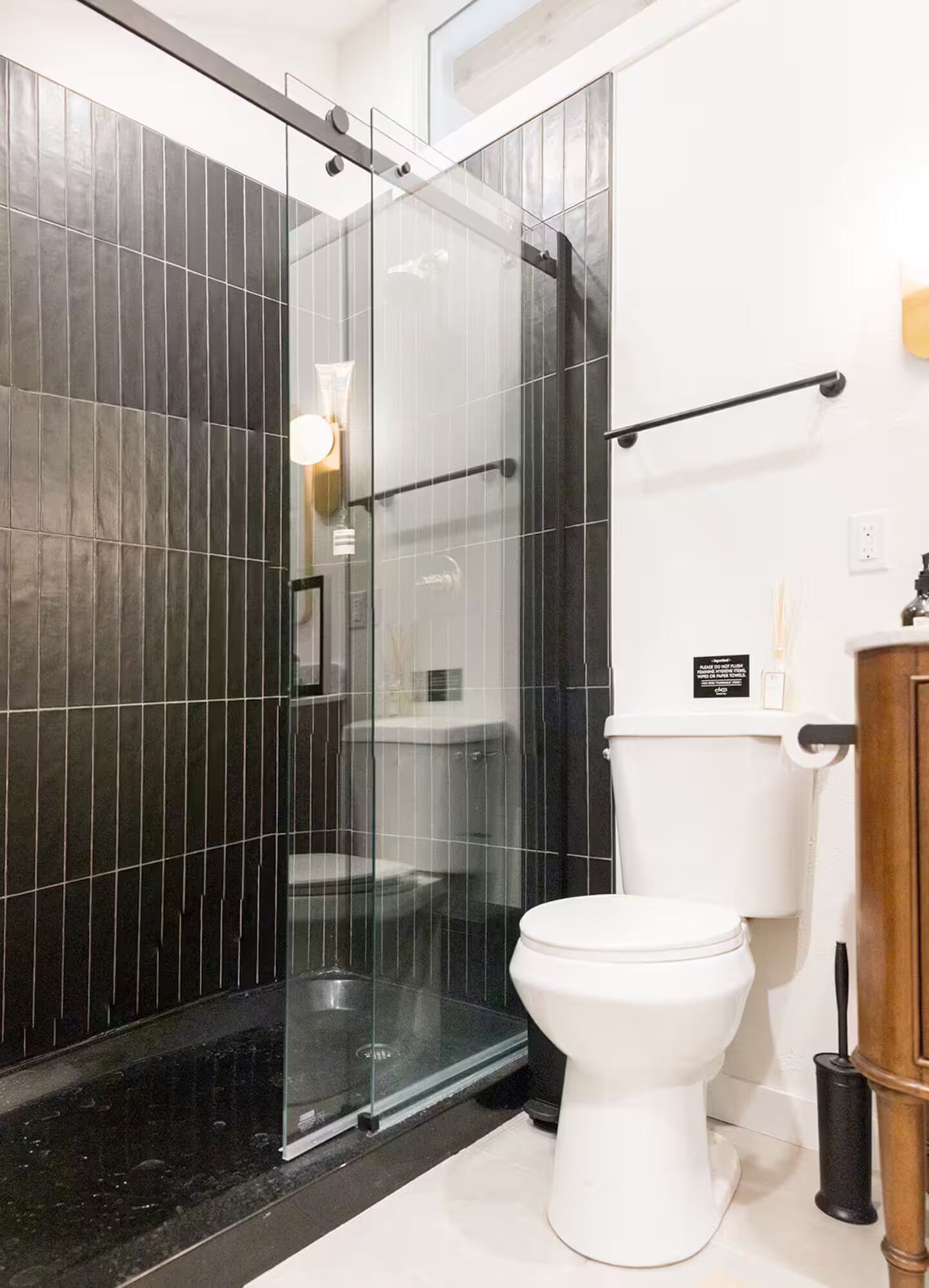 Une salle de bain moderne avec une douche à parois de verre, des toilettes blanches et un meuble en bois.