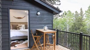 A wooden deck with a table and chairs, a small table lamp, and a framed picture of a bird on the wall.