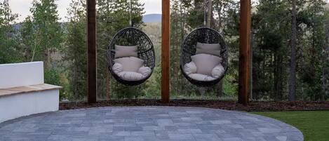 Un espacio de estar al aire libre con forma circular, con dos sillones colgantes y una pérgola.