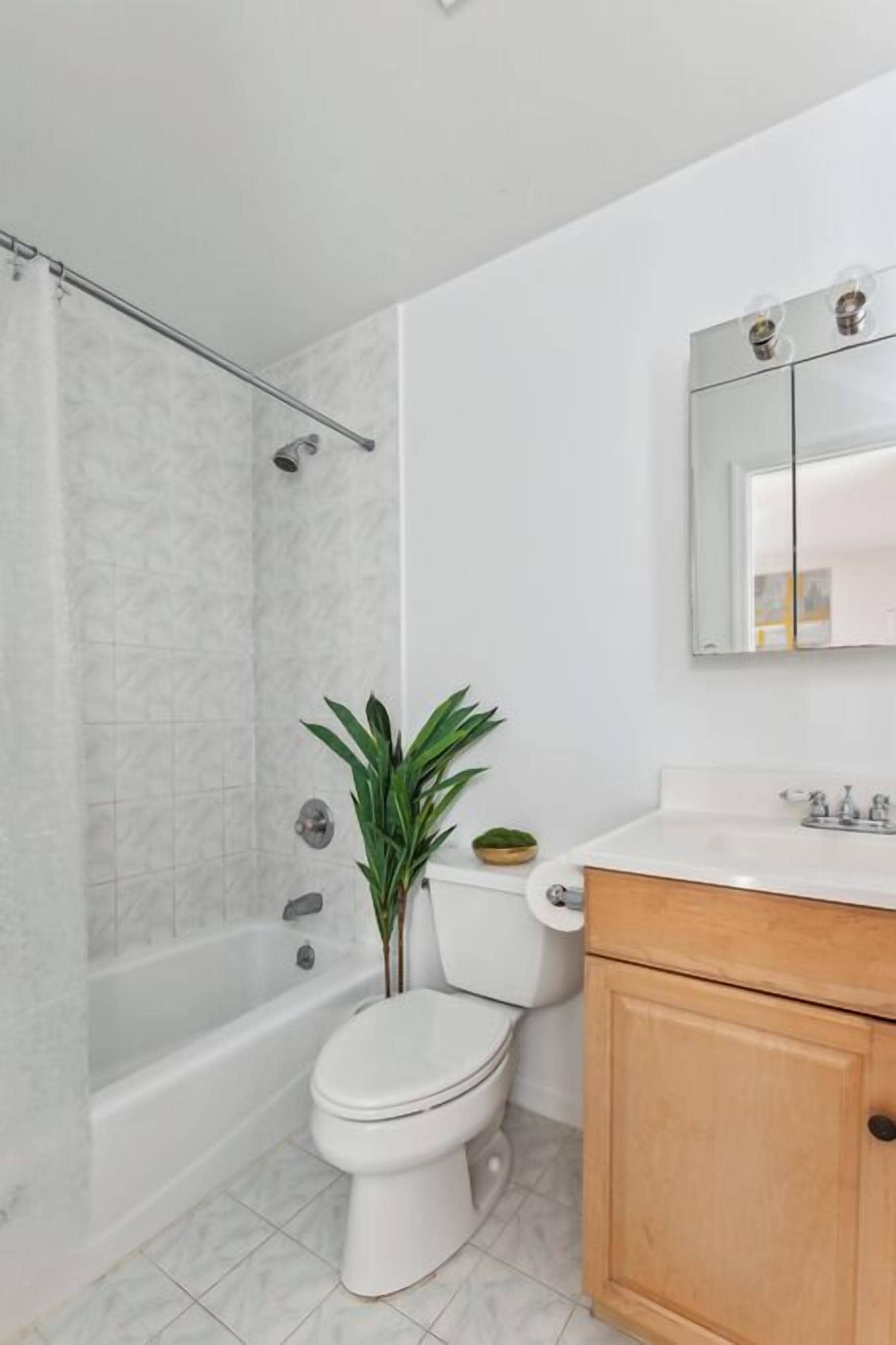 A bathroom with a bathtub, toilet, and a sink with a mirror above it.