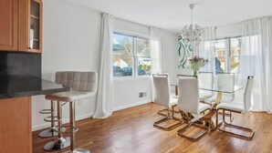 Una cocina moderna con un mueble de madera, un taburete de bar y una mesa de comedor con sillas blancas.