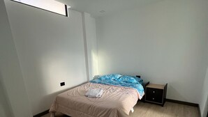 Un dormitorio con cama, mesita de noche y ventana.