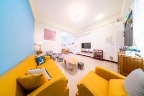 A living room with yellow sofas, a coffee table, and a TV. - Xiyue Homestay (Jinhu)