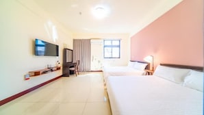 Une chambre d’hôtel avec deux lits, une télévision, un bureau et une fenêtre.