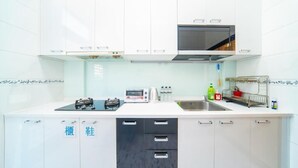 Une cuisine moderne avec des meubles blancs, un four encastré, un four à micro-ondes et un évier.
