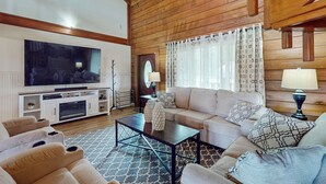 Un salon confortable avec un grand téléviseur à écran plat, un canapé, une table basse et une cheminée.