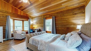 Une chambre aux murs lambrés, avec un grand lit, un canapé et un bureau.