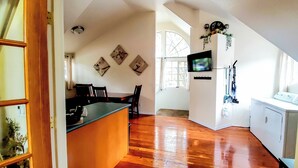 A spacious living area with hardwood flooring, a kitchen area with a washing machine, and a dining area with chairs and a table. - Explore Caves & Coast! Family-Friendly Oregon Stay (Cave Junction)