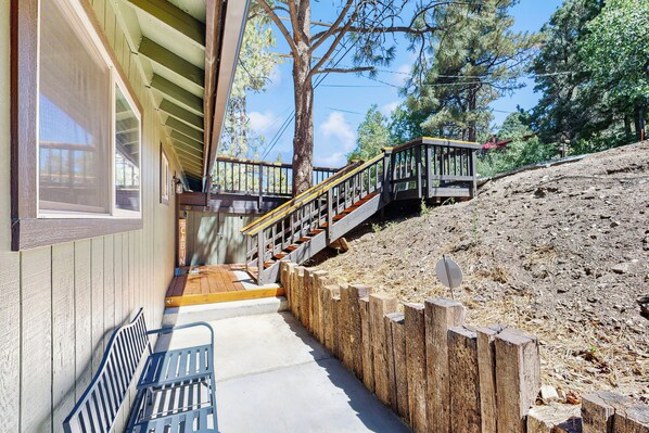 A wooden cabin with a porch, a staircase leading up to a deck, and a view of a forested hillside. - 2 Large Decks & Hot Tub! Big Bear Cabin Getaway (Big Bear)
