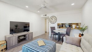 A modern living room with a flat-screen TV, a sofa, an ottoman, and a dining area with chairs and a table. - Mtn-View Balcony: Condo 6 Mi to Dtwn Phoenix (Phoenix)
