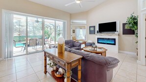 A spacious living room with a large TV, comfortable seating, and a ceiling fan. - Golfer's Oasis w/ Pool in Black Diamond Ranch! (Lecanto)