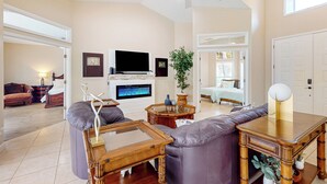 A spacious living room with a fireplace, a television, and a ceiling fan. - Golfer's Oasis w/ Pool in Black Diamond Ranch! (Lecanto)