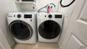 Ein Waschraum mit zwei Waschmaschinen, die von vorne geladen werden, und einem an der Wand angeschlossenen Schlauch.