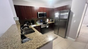 Eine moderne Küche mit Granit Arbeitsplatten, Edelstahlgeräten und dunklen Holzschränken.