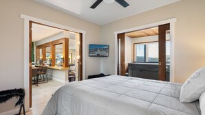 Ein Schlafzimmer mit einem großen Bett, Holztüren zu einem Balkon und einem Essbereich sowie Blick auf die Stadt.