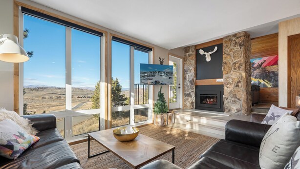 Ein geräumiges Wohnzimmer mit großem Fenster und Panoramablick, einem Kamin und einer gemütlichen Sitzecke.
