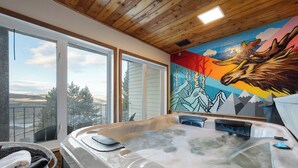 Ein Whirlpool mit Bergblick, einer Holzbalkendecke und einem Wandbild eines Elchs.