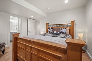 Een slaapkamer met een houten bed, bedlampjes en een deur naar een badkamer.