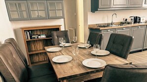 A dining area with a wooden table set for four, surrounded by leather chairs.