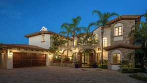 A large, multi-story house with a stone facade, multiple arches, and a spacious courtyard. - Casa Primera: 6BR Ocean-View Villa, Palmilla Dunes Club Access (San Jose del Cabo)