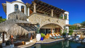 A luxurious villa with a stone facade, a pool, and outdoor seating. - Casa Primera: 6BR Ocean-View Villa, Palmilla Dunes Club Access (San Jose del Cabo)