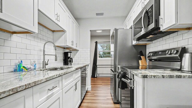 A modern kitchen with white cabinets, a stainless steel refrigerator, a microwave, and an oven. - Spacious 3BR Home Near Lake Hollingsworth (Lakeland)