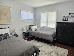 A bedroom with two beds, a dresser, a map on the wall, and two windows with blinds. - Spacious 5-bedroom house in charming Ypsilanti with AC (Ypsilanti)