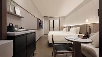 A compact hotel room with a bed, a small desk, a chair, a round table, and a wall-mounted TV.