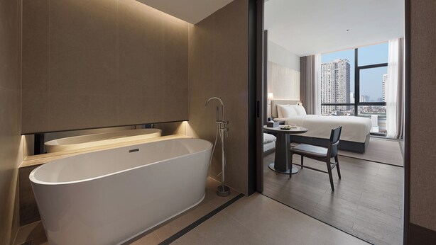 A modern bathroom with a freestanding bathtub, a shower, and a large window offering a city view. - K·SPACE Hotel - Guangzhou Beijing Road Dafo Ancient Temple Branch (Guangzhou)