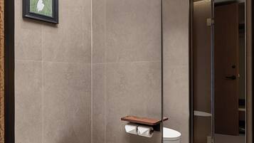 Un baño moderno con inodoro, un estante pequeño y un cuadro en la pared.