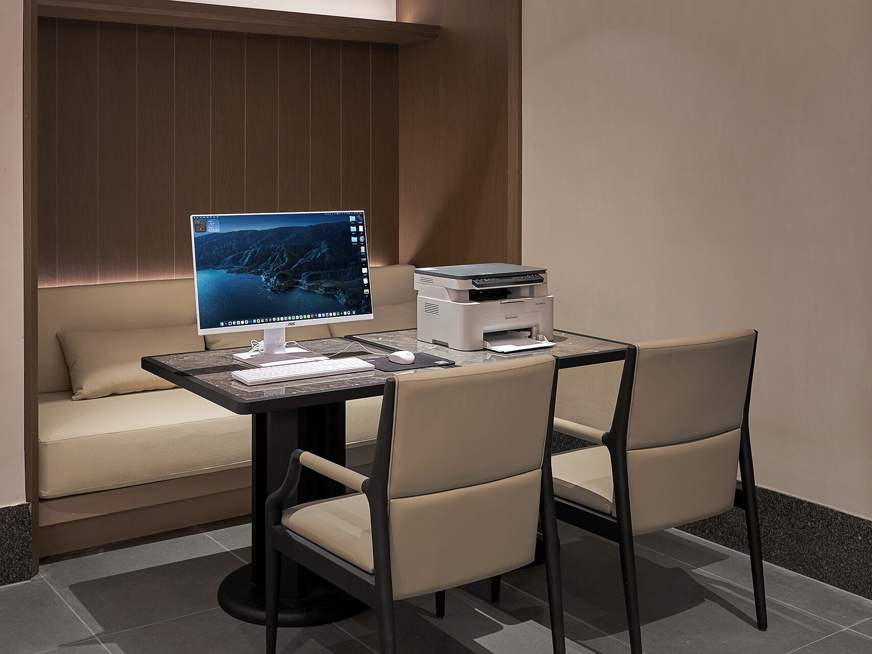 A modern office space with a desk, computer, printer, and two chairs.