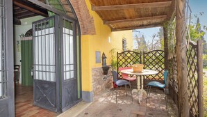 Une terrasse avec une table ronde et des chaises, une clôture en bois et une vue sur l’extérieur.