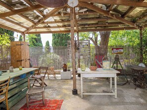 Eine Terrassengruppe im Freien mit Tisch, Stühlen und verschiedenen Gegenständen wie einer Waage und Töpfen.